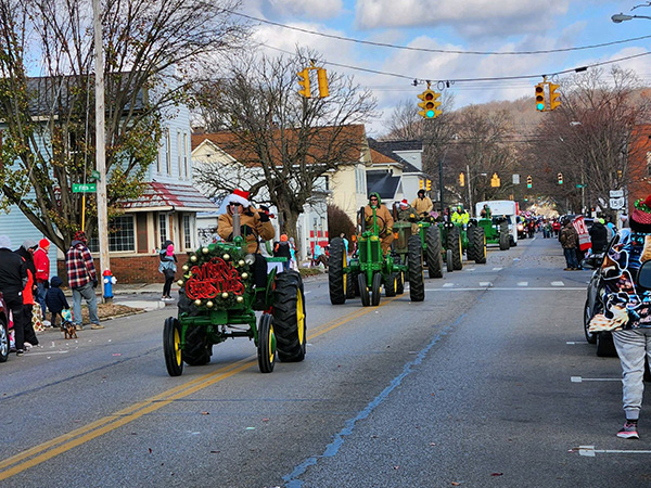 Green tractors with men in santa hats driving them