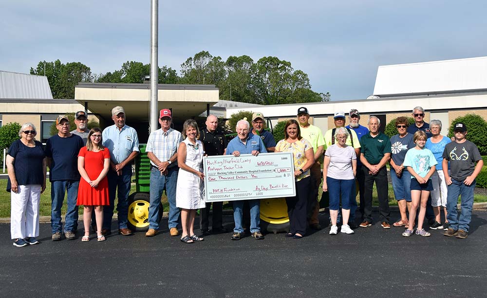 Club members and hospital foundation staff holding a $1,000 donation check outside the hospital